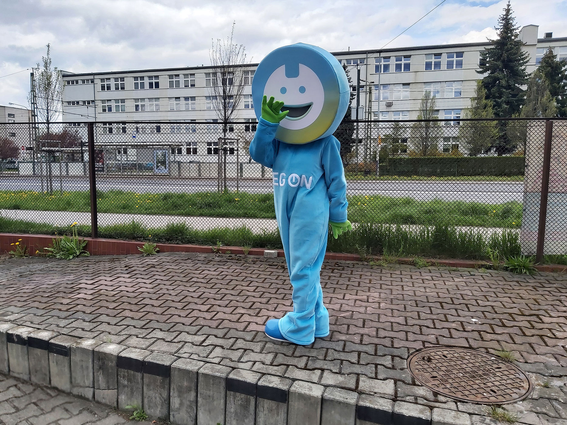 Maskotka strój w postaci chłopca pozująca do fotografii przed siedzibą firmy Elabika
